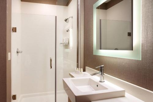 a bathroom with a sink and a shower with a mirror at SpringHill Suites by Marriott Coralville in Coralville