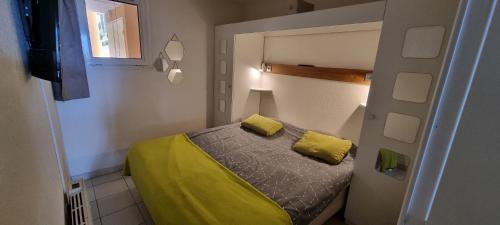 - une petite chambre avec un lit et des oreillers jaunes dans l'établissement 2 pièces vue panoramique sur mer et baie de Cannes, à Théoule-sur-Mer