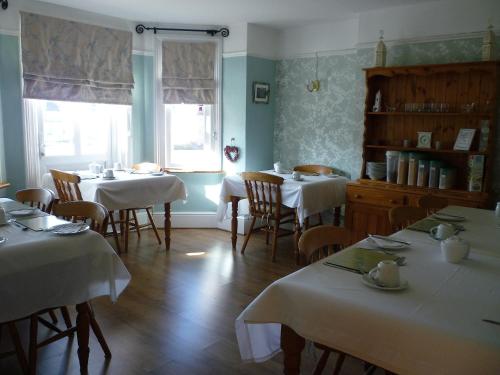 uma sala de jantar com mesas e cadeiras com toalha de mesa branca em The Norman Guest House em Dover