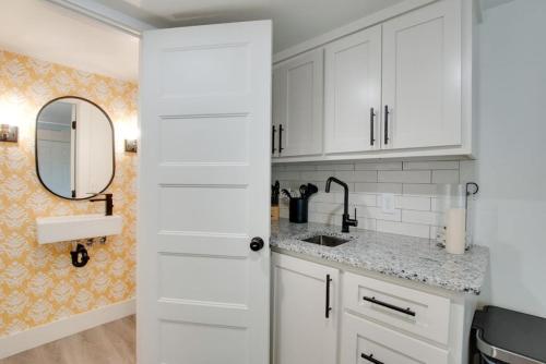 eine weiße Küche mit einem Waschbecken und einem Spiegel in der Unterkunft 15 Daisy Tiny Cottage Near Lake Guntersville in Scottsboro