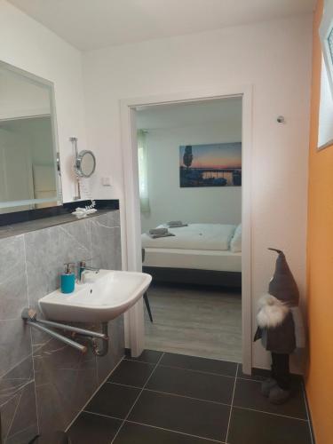 a bathroom with a sink and a bathroom with a bedroom at Bodensee Sunshine Zimmer & Apts. in Uhldingen-Mühlhofen