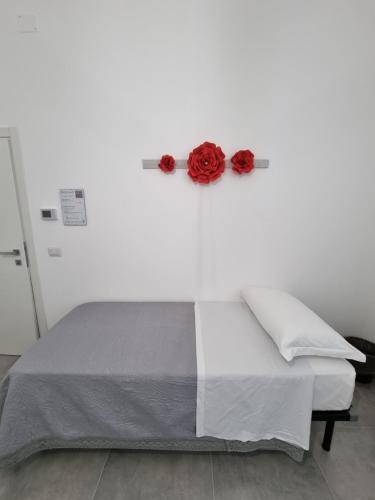 a bed with two red roses on a wall at CASA VERDi 37 CAMERA RUBINO SMERALDO in Porto SantʼElpidio