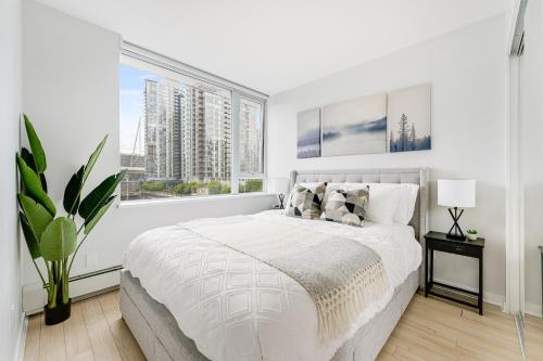 a white bedroom with a large bed and a window at Heart of Downtown 1 bd Entire Condo - Pool, Gym, Parking, Office, AC in Vancouver