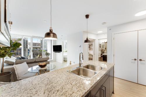 a kitchen with a sink and a living room at Heart of Downtown 1 bd - Pool, Gym, Parking, Office, AC in Vancouver