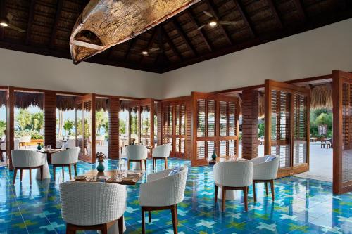 a restaurant with white chairs and tables and windows at Chablé Maroma in Playa del Carmen
