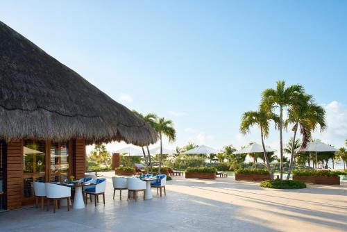 a restaurant with tables and chairs and palm trees at Chablé Maroma in Playa del Carmen
