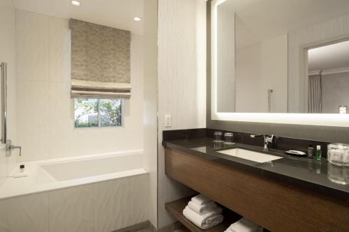 a bathroom with a sink and a tub and a mirror at The Westin Palo Alto in Palo Alto