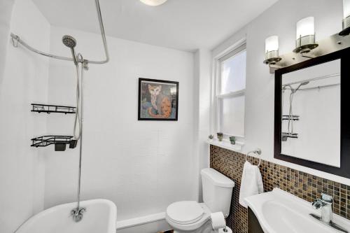 ein Badezimmer mit einem Waschbecken, einem WC und einem Spiegel in der Unterkunft Logan Square Coach House in Chicago