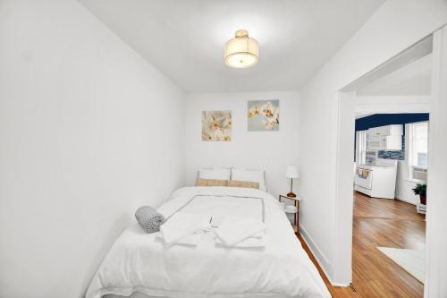 a white bedroom with a bed and a hallway at Logan Square Coach House in Chicago
