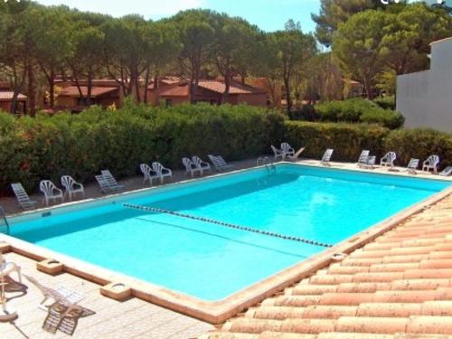 une grande piscine bleue avec des chaises dans l'établissement Studio Cabine à La Roquille, Piscine, Tennis, Parking, Proche Plages et Village Naturiste - FR-1-749-21, au Cap d'Agde