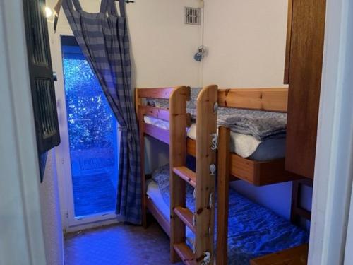 Cette chambre comprend 2 lits superposés et une porte. dans l'établissement Studio Cabine à La Roquille, Piscine, Tennis, Parking, Proche Plages et Village Naturiste - FR-1-749-21, au Cap d'Agde