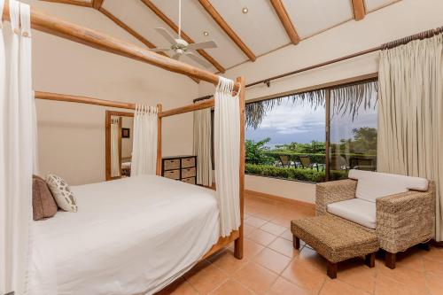 1 dormitorio con 1 cama, 1 silla y 1 ventana en Punta Islita Villas Luxury Destination, en Islita