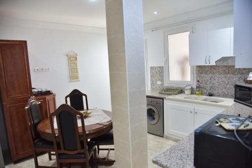 uma cozinha com uma mesa e cadeiras e um lavatório em Appartements neufs et modernes entre ter et mer em Soliman