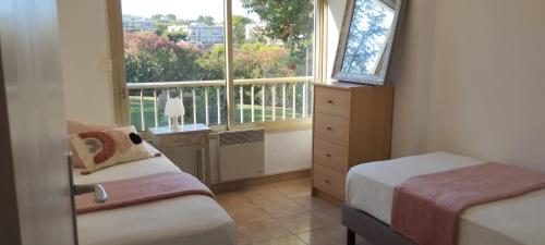 une petite chambre avec deux lits et une fenêtre dans l'établissement Escale au Val de la Mer, à Antibes