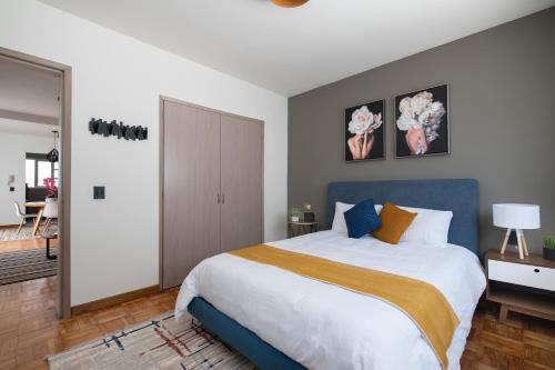 um quarto com uma cama grande e uma cabeceira azul em D.4 Acogedor departamento en la icónica Roma Norte em Cidade do México