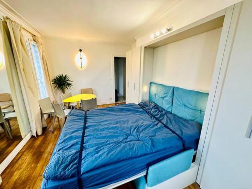 - un grand lit bleu dans une chambre avec une table dans l'établissement Studio « lescostreet » Les Halles : vue Tour Eiffel, à Paris