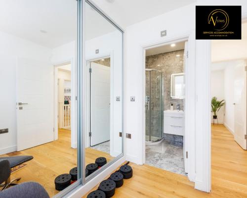 a bathroom with a glass walled shower and a mirror at Luxury Home by AV Stays Short Lets Sidcup in Sidcup