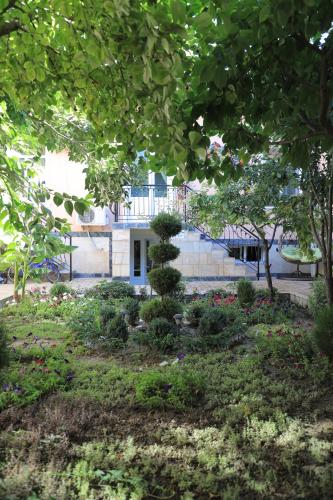 a garden with trees and flowers in front of a building at Nursultan Grand Guest House in Samarkand