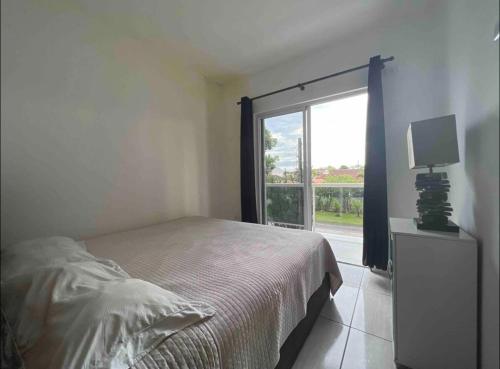 a bedroom with a bed and a large window at Residencial Passos in Guaratuba