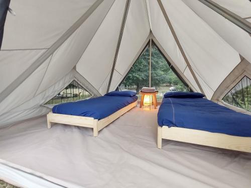 two beds in a canvas tent with a table at Camping Federico Farm in Pontremoli
