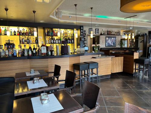 a restaurant with tables and chairs and a bar at Hotel Ammerländer Hof in Westerstede