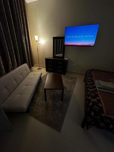 ein Wohnzimmer mit einem Sofa und einem Flachbild-TV in der Unterkunft Studio FLAT in Ajman in Ajman 