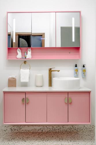 a pink bathroom with a sink and a mirror at The Pink Palm Hotel - Adults Only in Charlotte Amalie