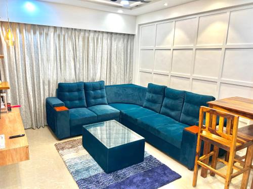 a living room with a blue couch and a table at Coco Loco Colva in Colva