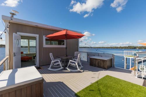 a deck with a table and chairs and an umbrella at New Floating Luxury: Unique Houseboat Retreat in Fleming Island