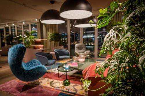 a living room with a couch and chairs and plants at Motel One Rotterdam in Rotterdam