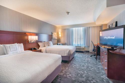 a hotel room with two beds and a flat screen tv at Courtyard by Marriott Silver Spring Downtown in Silver Spring
