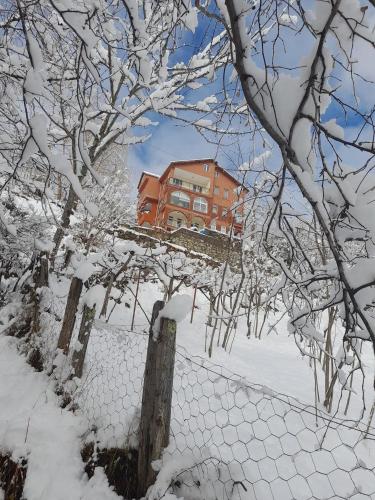 uma cerca coberta de neve com um edifício ao fundo em Çaykara Dağ Evi em Çaykara