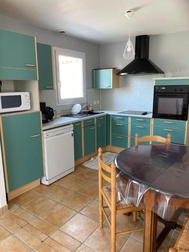 une cuisine avec des armoires vertes et une table à l'intérieur dans l'établissement Maison familiale La Baie 10 ps en côte de Jade, à La Bernerie-en-Retz