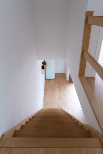 a staircase in a room with white walls and wooden floors at Prachtig duplex appartement met balkon te Wenduine in De Haan