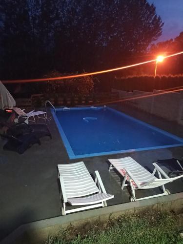 two lounge chairs and a swimming pool at night at Apartmani Drinski biseri Vrhpolje in Vrhpolje