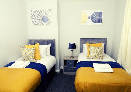 twee bedden in een kamer met geel en blauw bij Must stay 3 Bedroom house near Greenwich and Blackheath- Ideal for families and contractors in Londen