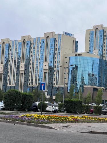 un grand bâtiment avec des voitures garées dans un parking dans l'établissement Набережная Астаны, à Astana