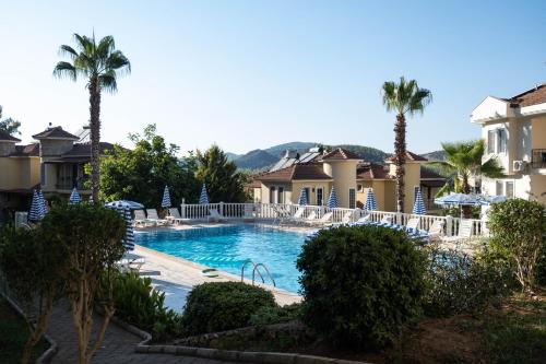 a swimming pool in a resort with palm trees at Nicholas Apartment Ölüdeniz in Fethiye