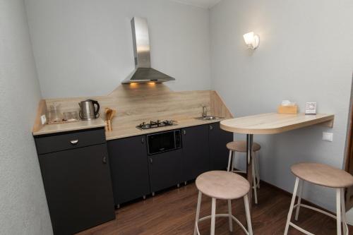 kuchnia z czarnymi szafkami oraz stołem i stołkami w obiekcie Hillside Guest House w Erywaniu