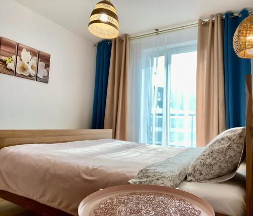 a bedroom with a bed with blue curtains and a window at Panda in Wrocław