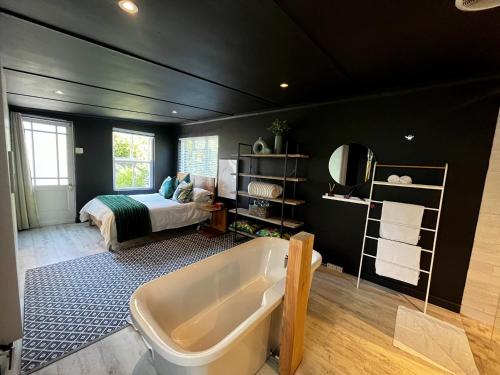 a bathroom with a bath tub and a bed at Modern Spacious Cottage with Hot Tub, Flora Studio in Hermanus