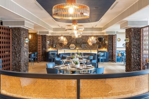 a dining room with tables and chairs and chandeliers at Delta Hotels by Marriott Giardini Naxos in Giardini Naxos