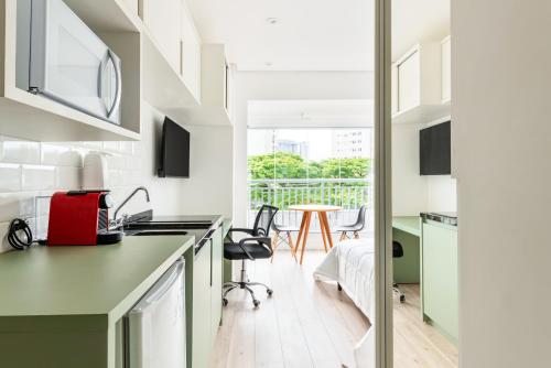 a kitchen with green cabinets and a table with chairs at Tabas - Edifício Walk SP in São Paulo