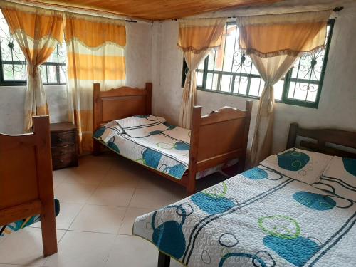 a bedroom with two beds and two windows at Cabaña La Esperanza in Paipa