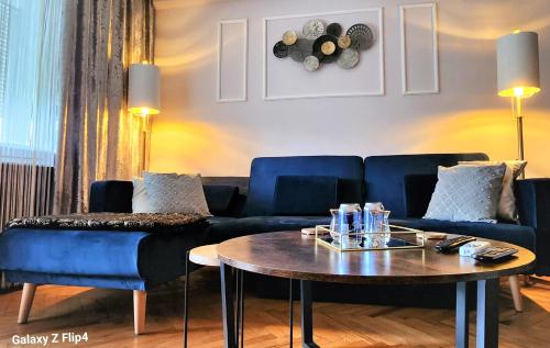 - un salon avec un canapé bleu et une table dans l'établissement JAWORSKI APART'S - Apartament Deluxe 40m2-balkon z widokiem na panorame miasta SELF CHECK IN 24H Apartament samoobsługowy- bezkontaktowe samodzielne zameldowanie przez 24h - FV, à Wrocław