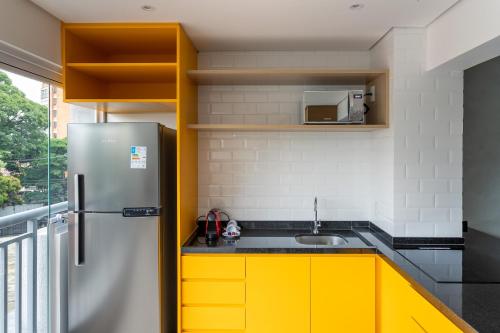 a kitchen with yellow cabinets and a stainless steel refrigerator at Tabas - Edifício Walk SP in São Paulo