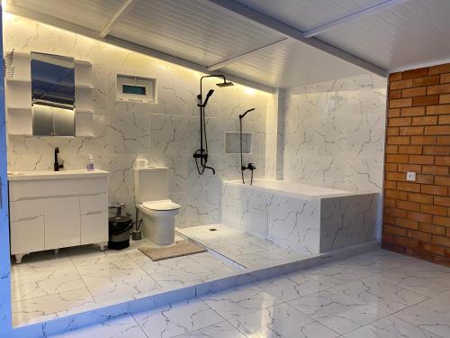 a white bathroom with a tub and a toilet at Duplex 80A in Tashkent