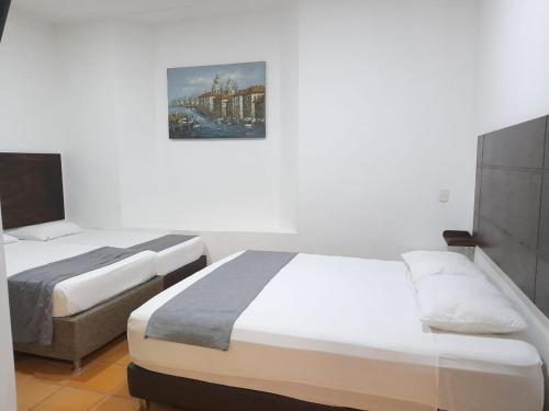 1 dormitorio con 2 camas y una foto en la pared en hotel san nicolas colonial en Barranquilla