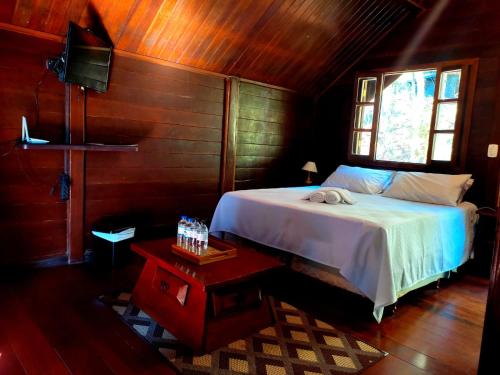 1 dormitorio con cama, ventana y mesa en Pássaro de Fogo, en Santo Antônio do Pinhal