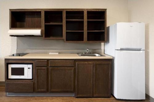 a kitchen with a white refrigerator and a sink at WoodSpring Suites Miami Southwest in Kendall